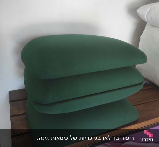 כריות ספה מרופדות בבד ירוק לצד מילוי כריות לבן בבית מלאכה